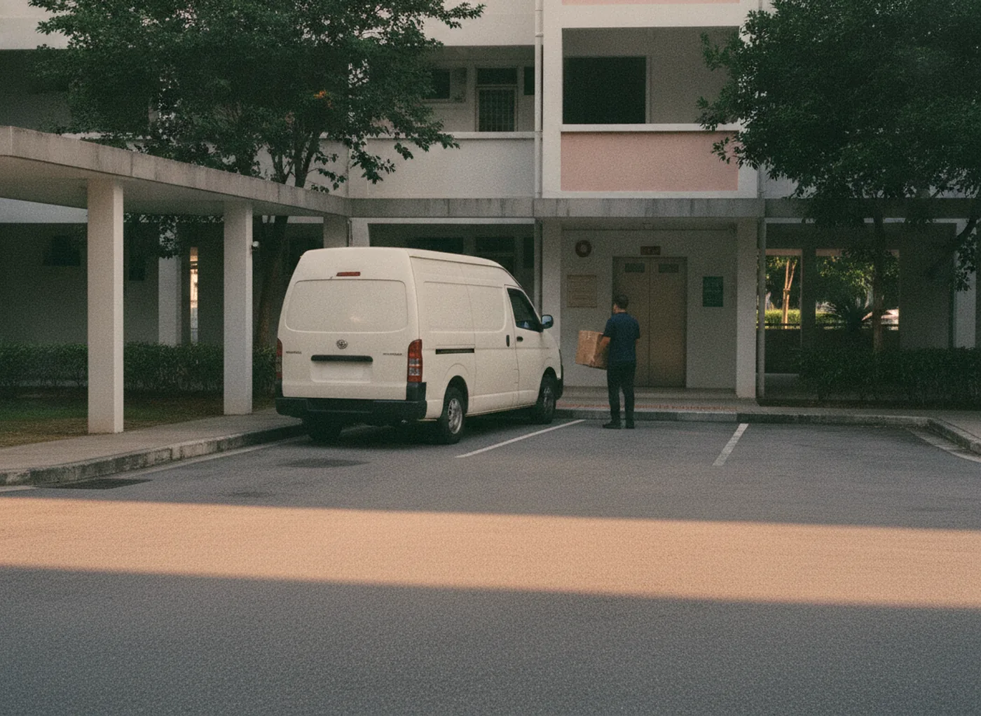 Delivery van at a Singapore residential block, courier carrying a carton to the lift lobby
